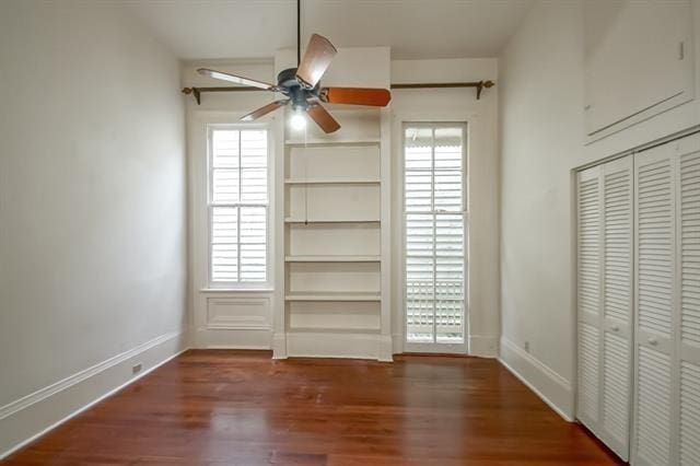 unfurnished bedroom with wood finished floors, baseboards, and multiple windows