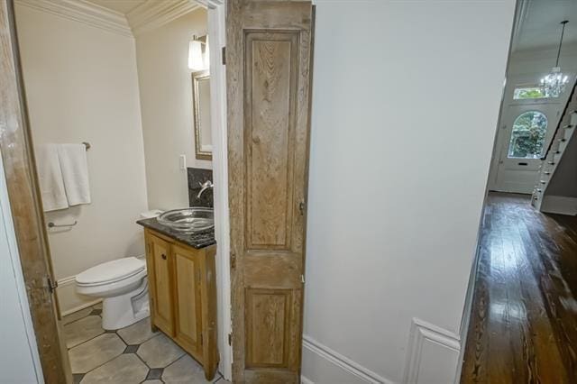 bathroom with wood finished floors, toilet, vanity, crown molding, and baseboards