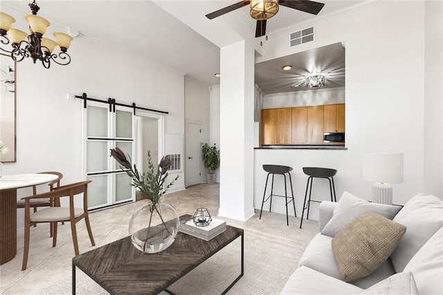 living area with a barn door, visible vents, ornamental molding, and ceiling fan with notable chandelier