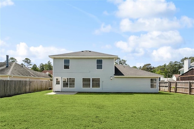 back of property with a shingled roof, a fenced backyard, and a yard