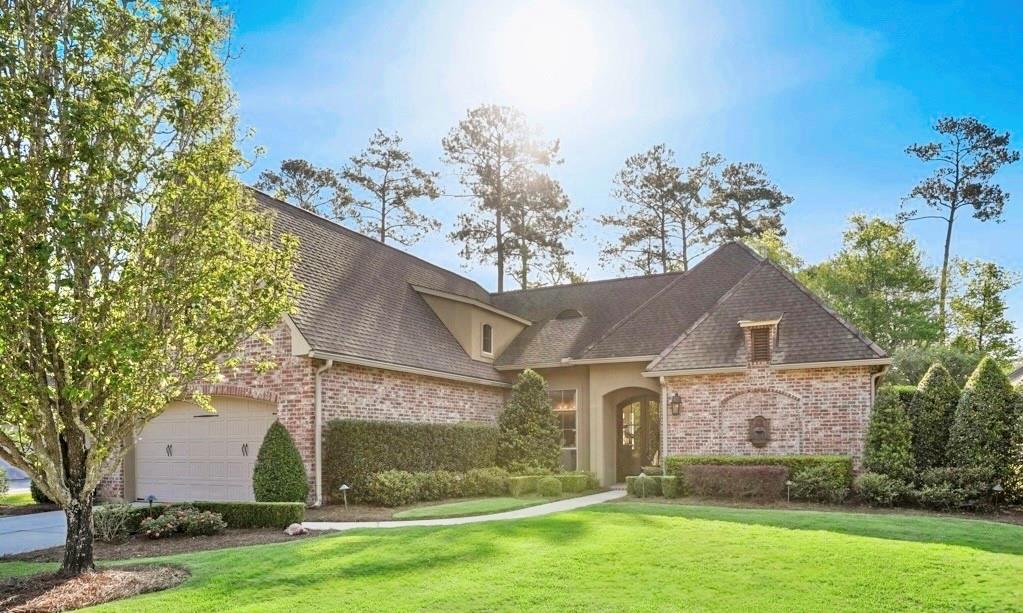 view of front of property featuring stucco siding, a front lawn, and brick siding
