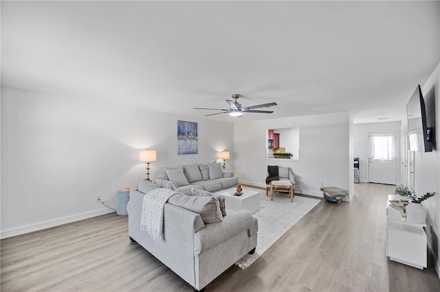 living room with ceiling fan, baseboards, and wood finished floors