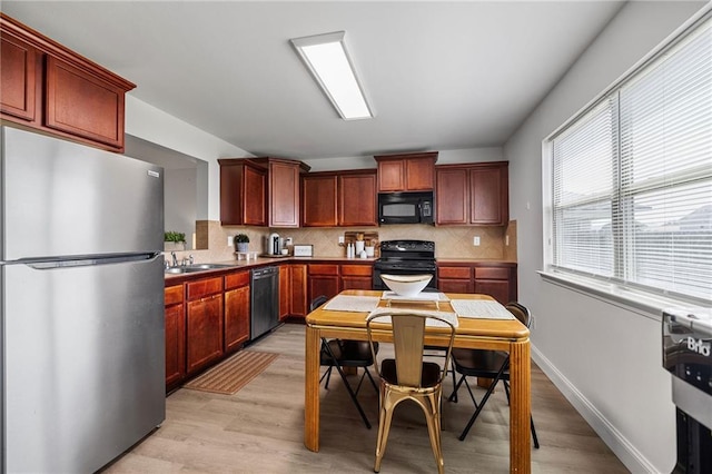 kitchen with dark brown cabinets, tasteful backsplash, light wood-style floors, and black appliances