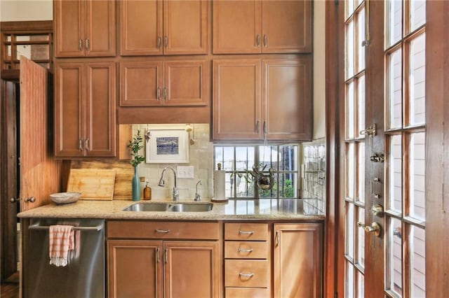 925 Touro St, New Orleans, LA 70116 - kitchen featuring stainless steel dishwasher, a sink, tasteful backsplash, brown cabinets, and light stone countertops