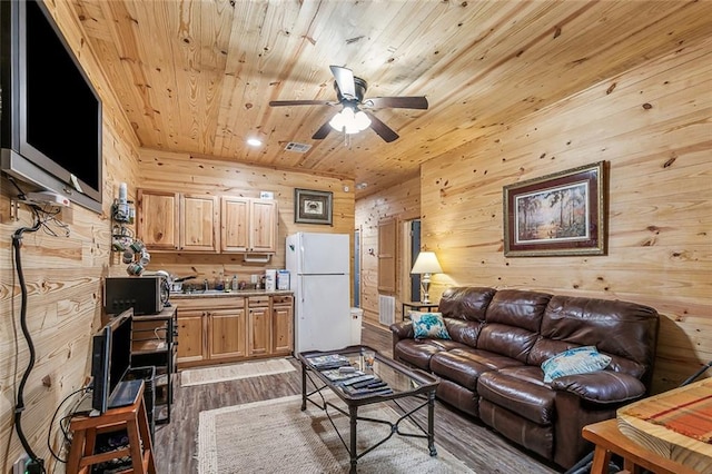 living area featuring wooden walls, visible vents, wooden ceiling, dark wood-type flooring, and ceiling fan