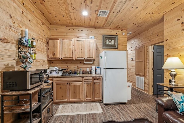 kitchen with wood ceiling, stainless steel microwave, wood walls, and freestanding refrigerator