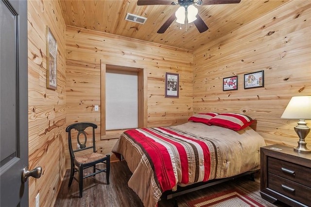 bedroom featuring visible vents, wood walls, wood finished floors, ceiling fan, and wooden ceiling