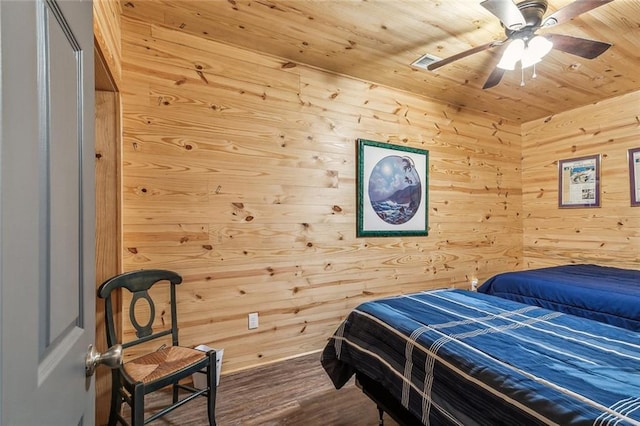 bedroom with visible vents, a ceiling fan, wood walls, wood finished floors, and wooden ceiling