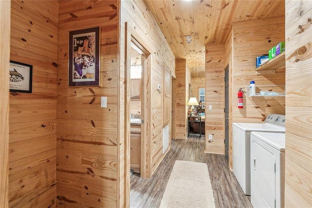 laundry area with wooden walls, washing machine and clothes dryer, light wood finished floors, and laundry area