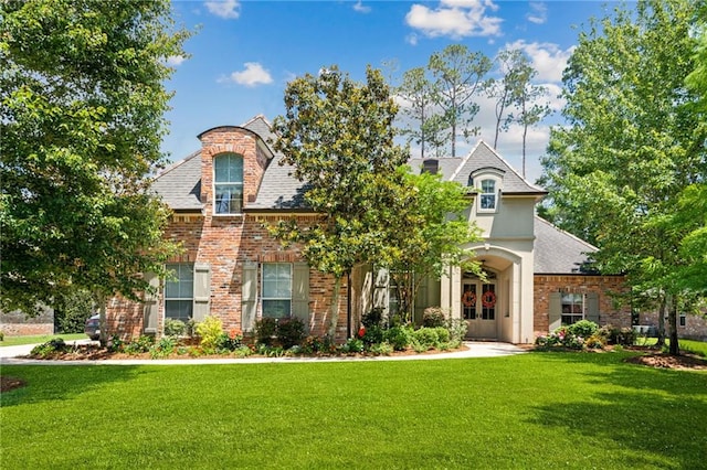 view of front facade with a front lawn, brick siding, and french doors