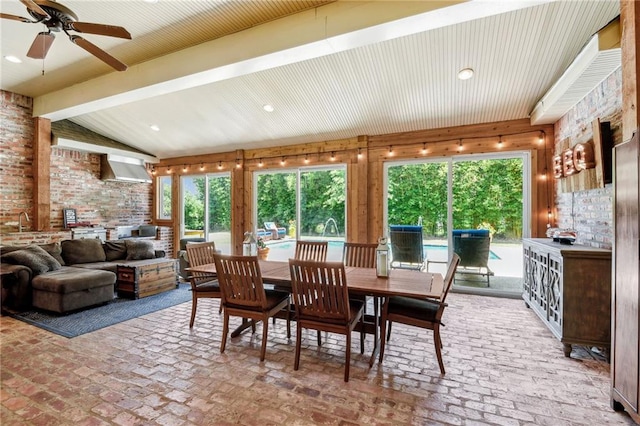 dining space with brick floor, a healthy amount of sunlight, lofted ceiling with beams, and ceiling fan