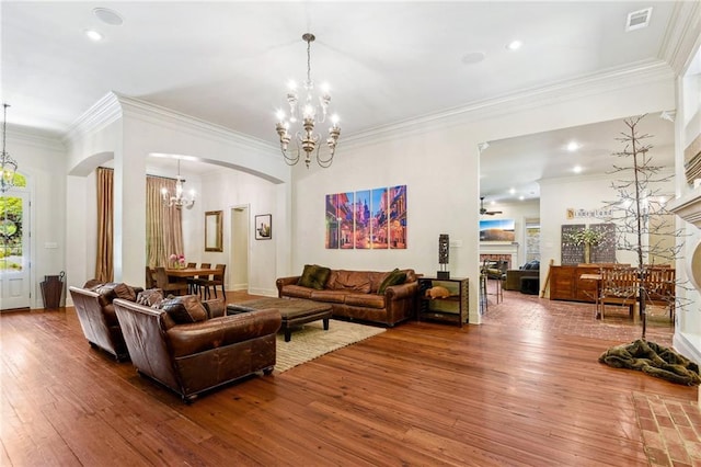 living room with arched walkways, visible vents, a notable chandelier, hardwood / wood-style floors, and ornamental molding