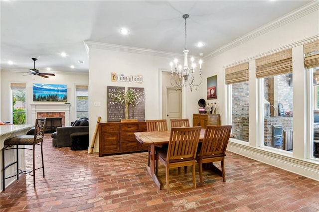 dining area featuring ceiling fan with notable chandelier, brick floor, and ornamental molding