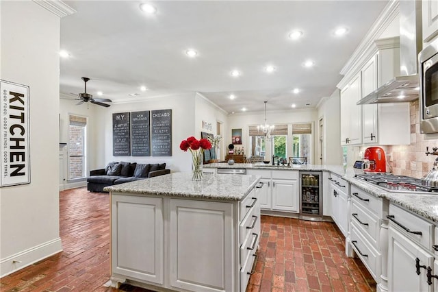 kitchen with brick floor, wine cooler, appliances with stainless steel finishes, and a peninsula