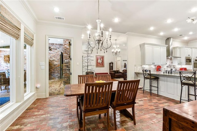 dining space with brick floor, visible vents, a chandelier, and crown molding