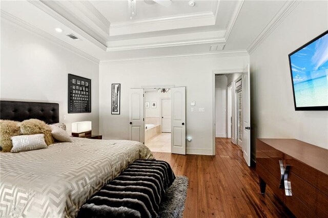 bedroom featuring hardwood / wood-style flooring, ornamental molding, visible vents, and a raised ceiling