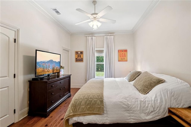 bedroom featuring wood finished floors, visible vents, baseboards, and ornamental molding