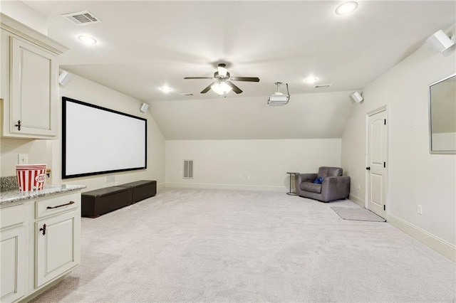 home theater room with lofted ceiling, light carpet, and visible vents