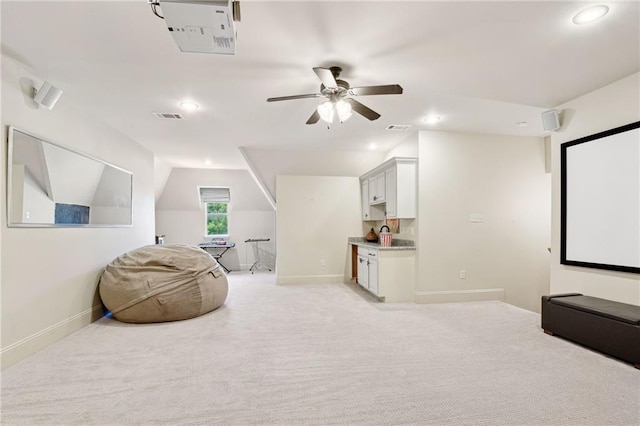 home theater with baseboards, vaulted ceiling, visible vents, and a ceiling fan