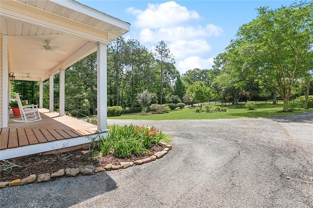 exterior space featuring a ceiling fan, a lawn, and covered porch