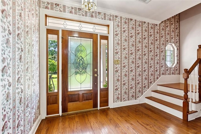 foyer featuring hardwood / wood-style floors, wallpapered walls, baseboards, and a wealth of natural light