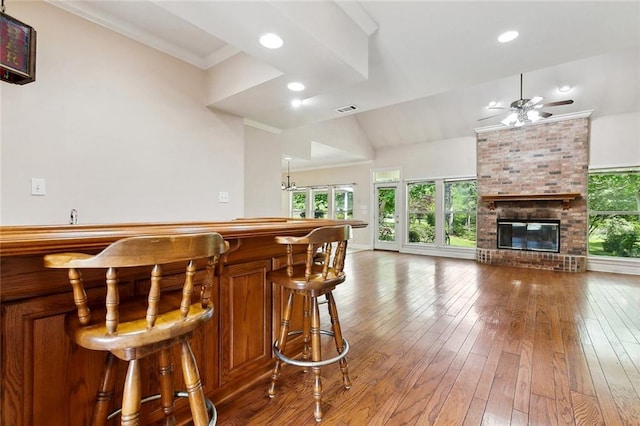 bar featuring a ceiling fan, a bar, hardwood / wood-style floors, a fireplace, and visible vents