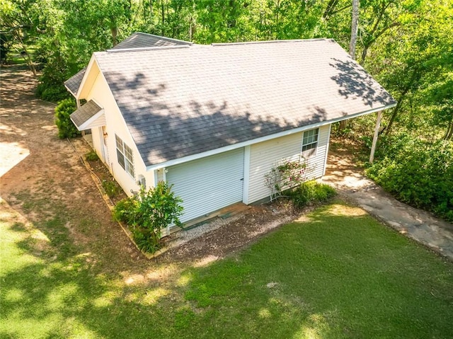 view of side of property featuring a lawn and a shingled roof