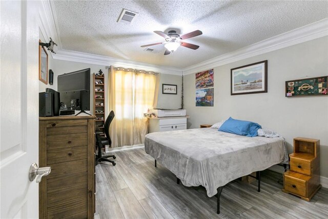 bedroom featuring wood finished floors, a textured ceiling, ceiling fan, ornamental molding, and visible vents