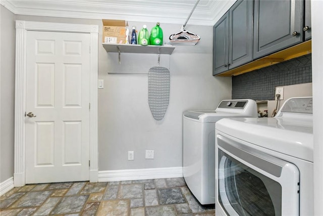 washroom with baseboards, cabinet space, stone finish flooring, crown molding, and washer and dryer