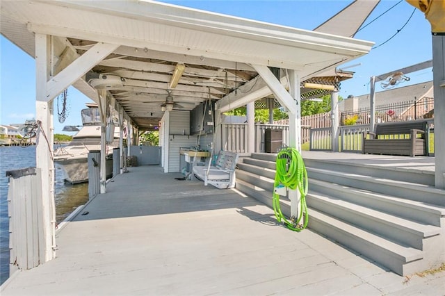 view of patio / terrace featuring fence, a water view, and a dock