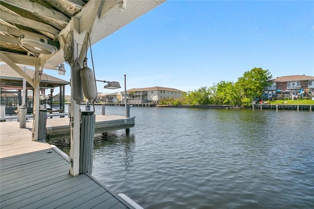 dock area featuring boat lift, a water view, and a residential view