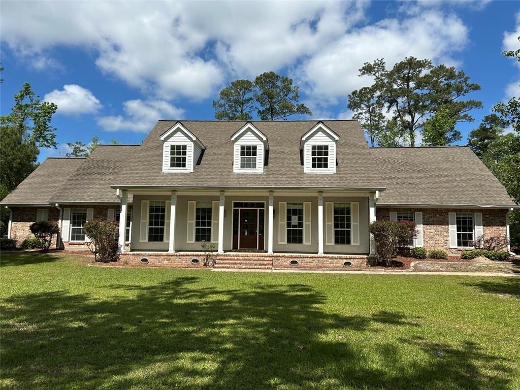 cape cod home with a shingled roof, a front lawn, and covered porch