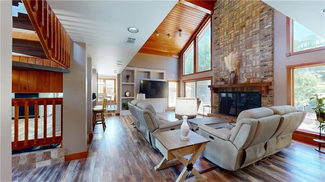 31765 River Pines Dr, Springfield, LA 70462 - living room featuring high vaulted ceiling, wood finished floors, a stone fireplace, baseboards, and visible vents
