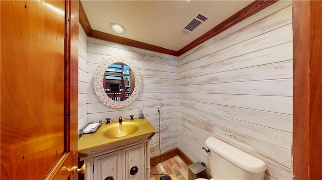 31765 River Pines Dr, Springfield, LA 70462 - half bathroom featuring toilet, visible vents, wood walls, crown molding, and vanity