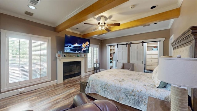 31765 River Pines Dr, Springfield, LA 70462 - bedroom featuring a barn door, wood finished floors, visible vents, and crown molding