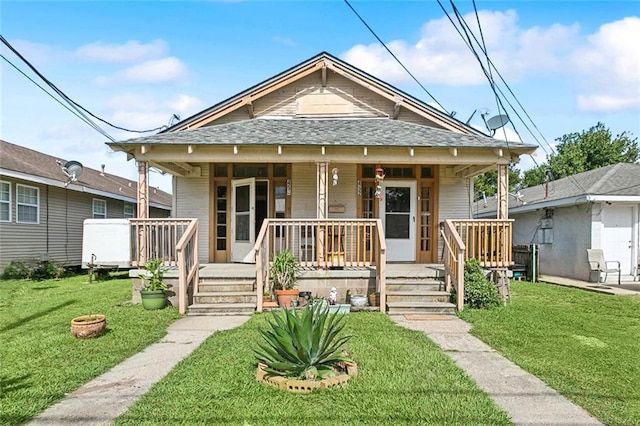 view of front facade with a front lawn, roof with shingles, and a porch