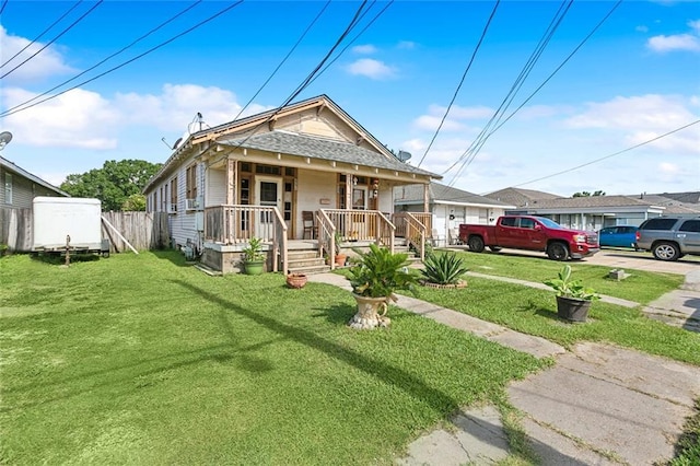 view of front facade with a porch, a front lawn, and fence