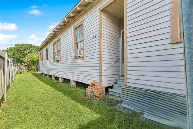 view of property exterior with a lawn, fence, cooling unit, and entry steps