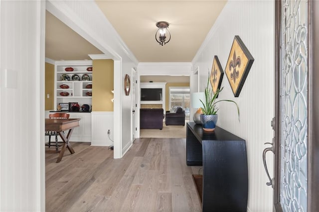 hallway with wood finished floors, built in features, and ornamental molding