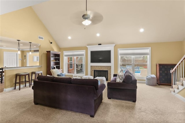 carpeted living room with stairway, visible vents, baseboards, a fireplace, and ceiling fan