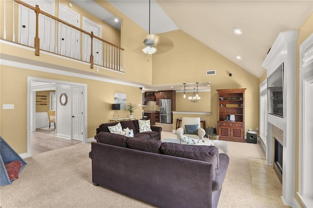 living area featuring a fireplace with flush hearth, high vaulted ceiling, visible vents, and light colored carpet