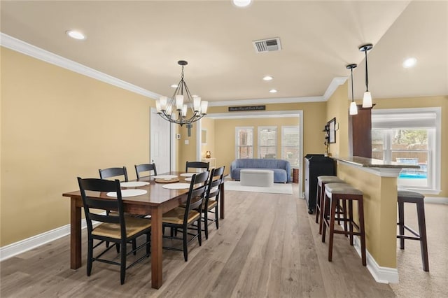dining space featuring light wood-style flooring, baseboards, visible vents, a notable chandelier, and ornamental molding