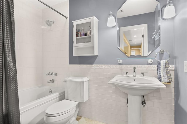 full bathroom with shower / tub combo, toilet, a wainscoted wall, and tile walls