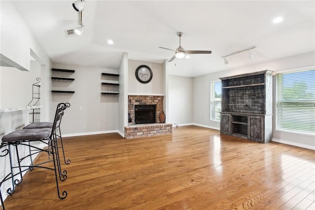 living area featuring a brick fireplace, visible vents, and rail lighting