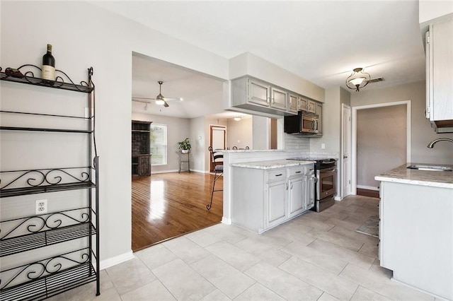 kitchen with tasteful backsplash, a sink, appliances with stainless steel finishes, ceiling fan, and baseboards