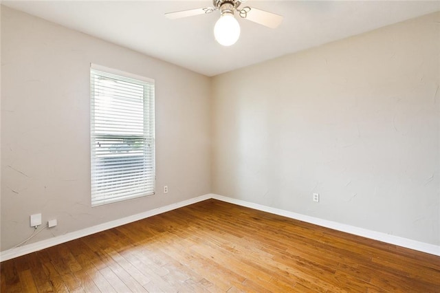 spare room featuring hardwood / wood-style flooring, a ceiling fan, and baseboards