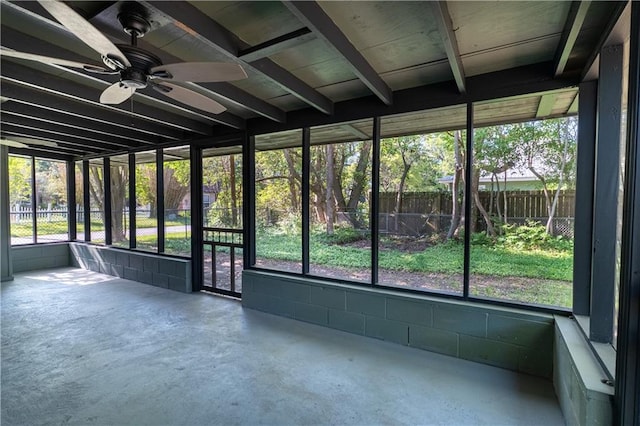 unfurnished sunroom featuring a ceiling fan and beam ceiling
