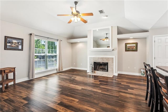 unfurnished living room with a tiled fireplace, vaulted ceiling, baseboards, a ceiling fan, and wood finished floors