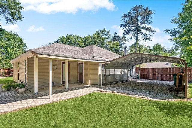 back of property featuring driveway, a carport, fence, a yard, and roof with shingles