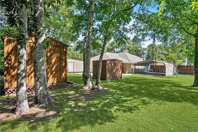 view of yard featuring a detached carport, an outbuilding, a shed, and fence